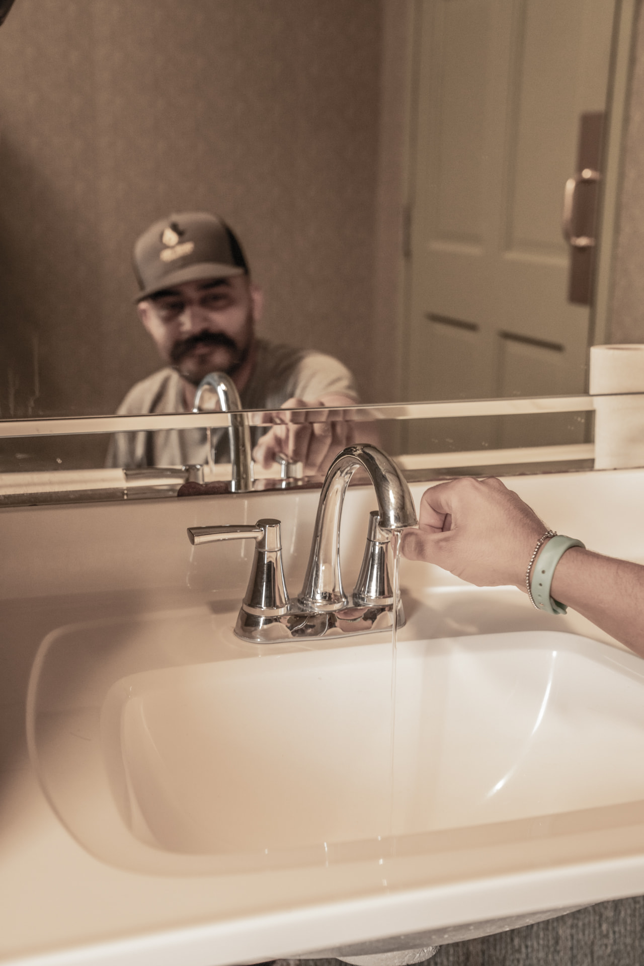Plumber testing water flow at a newly installed bathroom faucet